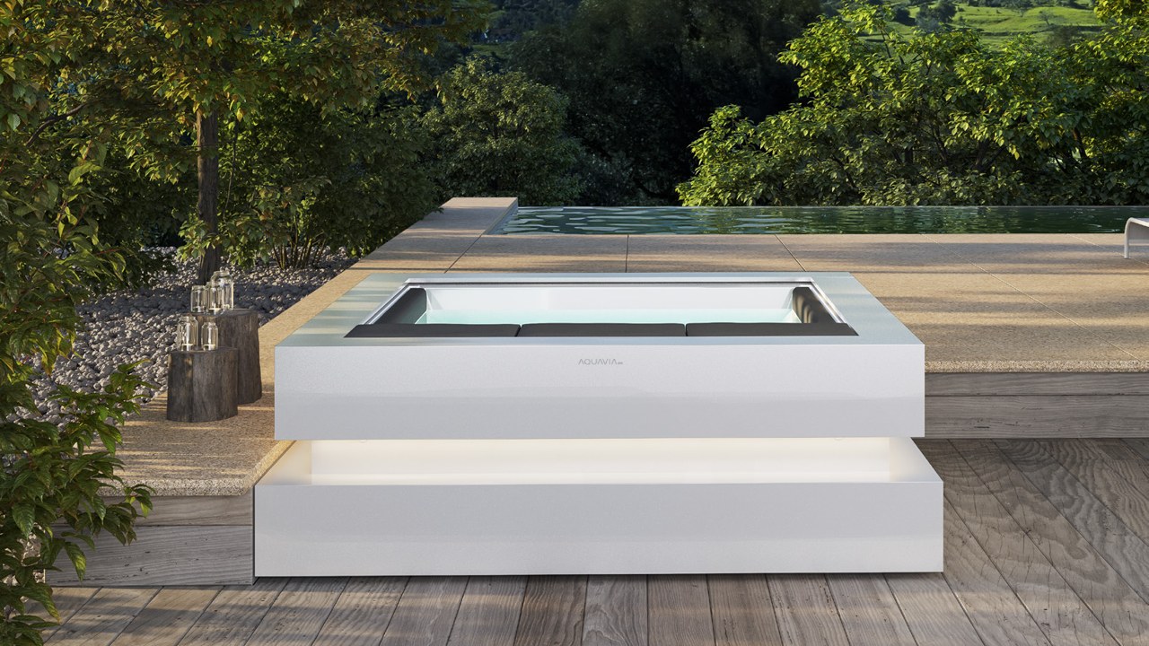 Spa Cube en blanco con base iluminada en terraza de madera junto a alberca